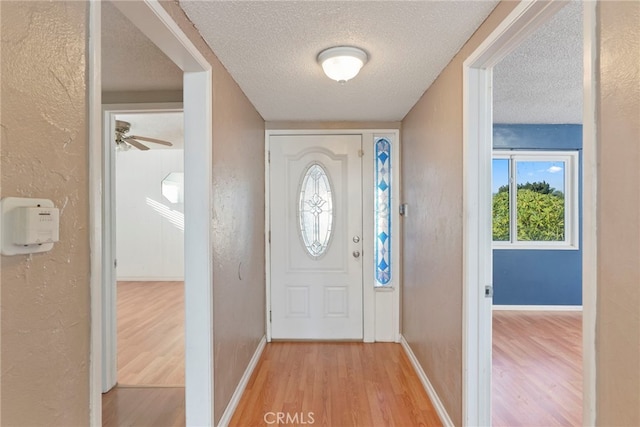 entryway with a textured ceiling, hardwood / wood-style flooring, and ceiling fan