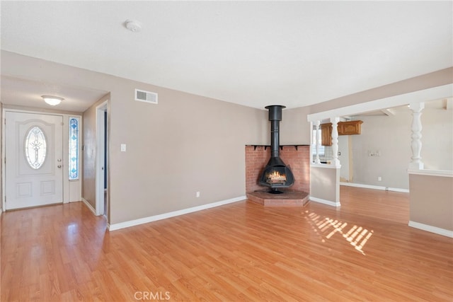 unfurnished living room with a wood stove and light wood-type flooring