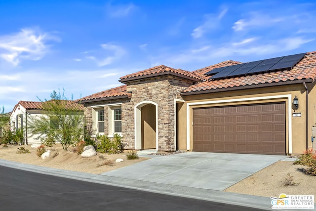 mediterranean / spanish home featuring solar panels and a garage