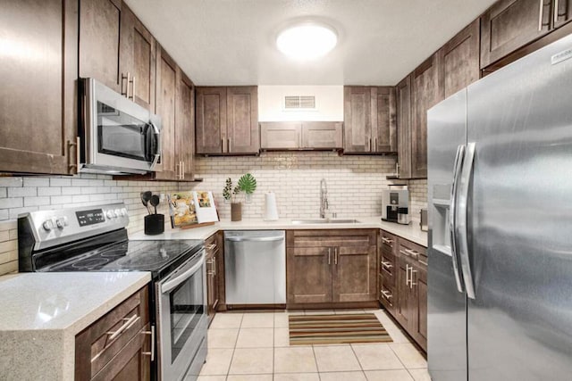 kitchen with light tile patterned floors, stainless steel appliances, tasteful backsplash, and sink