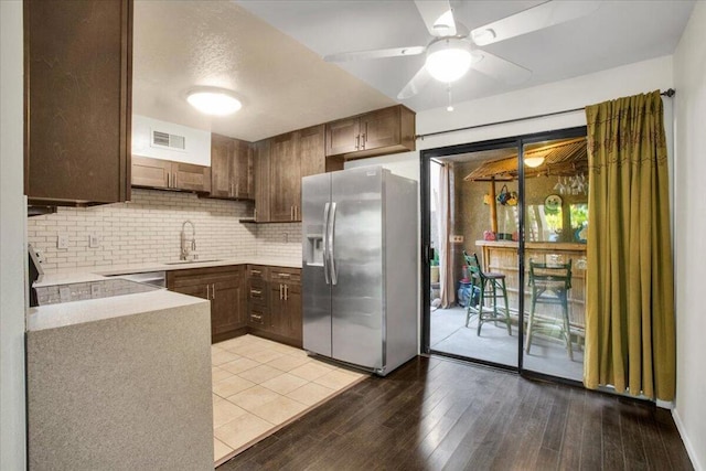 kitchen with sink, stainless steel fridge, stove, decorative backsplash, and light wood-type flooring