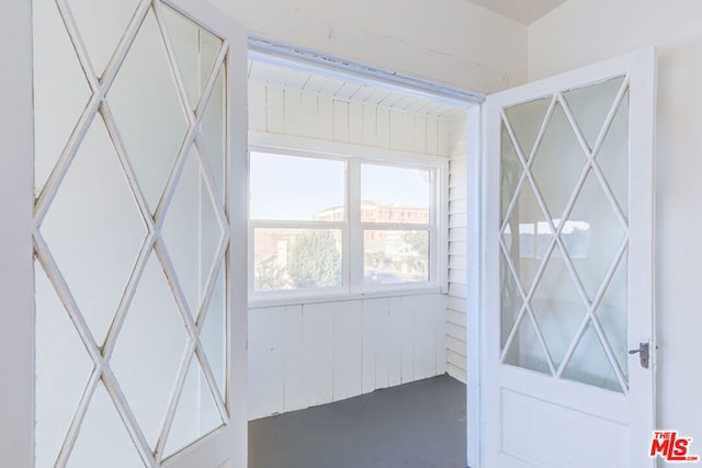 doorway featuring wooden walls and concrete floors