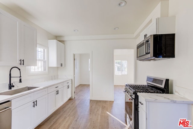 kitchen featuring white cabinets, light wood-type flooring, stainless steel appliances, and sink