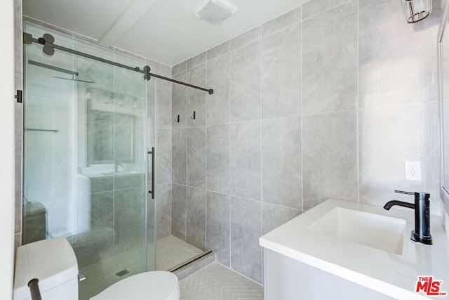 bathroom featuring an enclosed shower, vanity, toilet, and tile walls