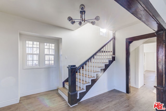 stairs featuring an inviting chandelier and hardwood / wood-style flooring