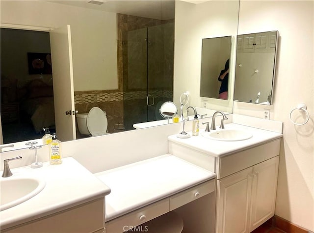 bathroom with vanity, a shower with shower door, and toilet