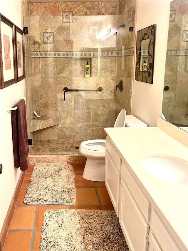 bathroom featuring tiled shower, vanity, tile patterned floors, and toilet