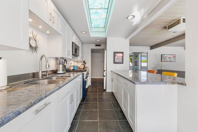 kitchen featuring sink, appliances with stainless steel finishes, stone countertops, beam ceiling, and white cabinetry