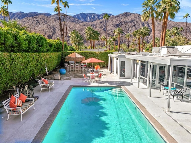 view of swimming pool with a mountain view, a patio, and a sunroom