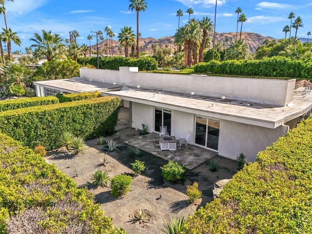 back of property with a mountain view and a patio area