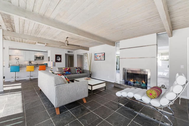 living room featuring beam ceiling, wooden ceiling, and a wealth of natural light