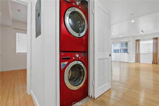 washroom with light hardwood / wood-style flooring and stacked washer and clothes dryer