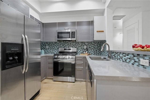 kitchen with gray cabinetry, sink, stainless steel appliances, and light hardwood / wood-style floors