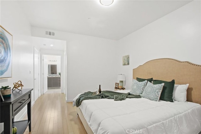 bedroom featuring ensuite bathroom and light wood-type flooring