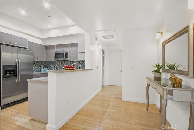 kitchen featuring light hardwood / wood-style floors, gray cabinets, kitchen peninsula, and stainless steel appliances