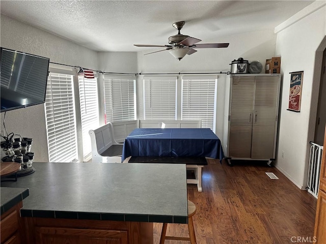 dining room featuring ceiling fan, dark wood-type flooring, and a textured ceiling