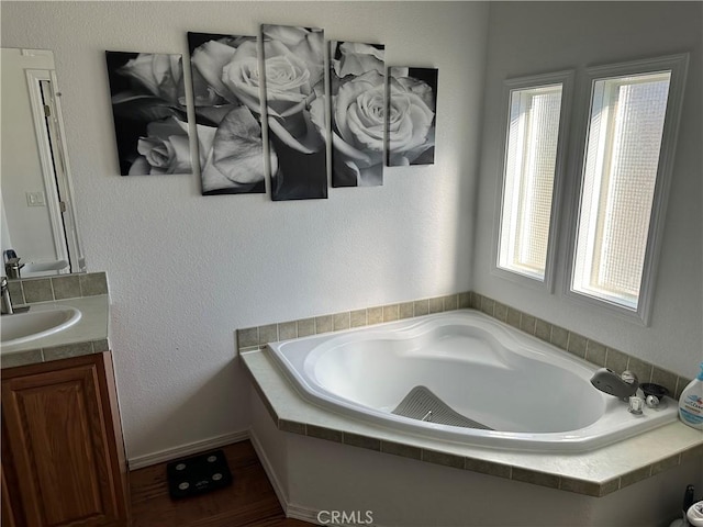 bathroom with vanity, wood-type flooring, and tiled tub