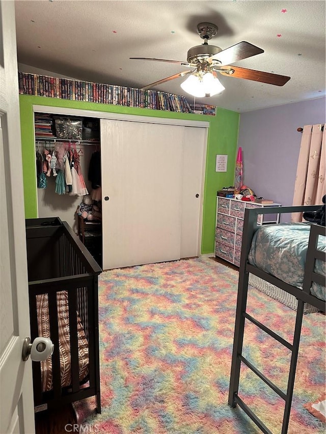 carpeted bedroom featuring ceiling fan, a closet, and a textured ceiling