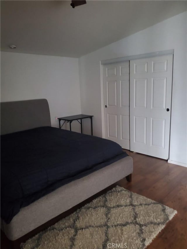 bedroom featuring dark hardwood / wood-style flooring, lofted ceiling, and a closet