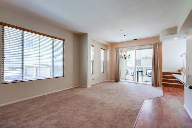 unfurnished living room featuring carpet and a chandelier