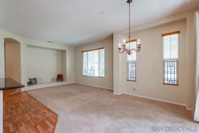 unfurnished living room with a chandelier and carpet floors