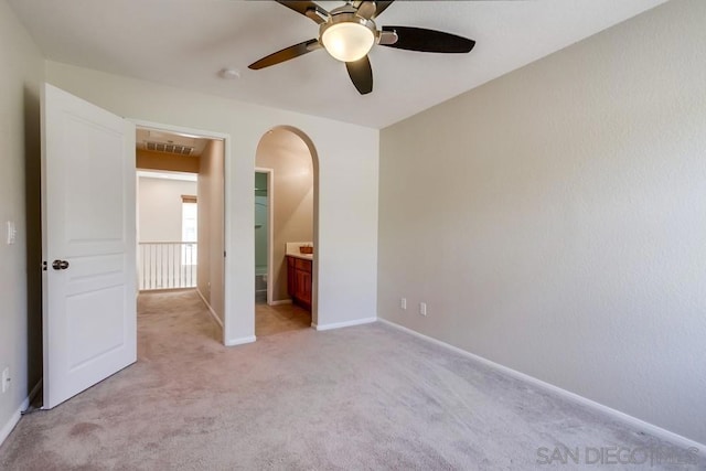 unfurnished bedroom with connected bathroom, light colored carpet, and ceiling fan