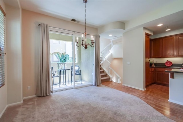 unfurnished dining area with light hardwood / wood-style floors and an inviting chandelier