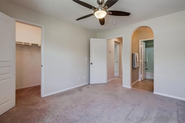 unfurnished bedroom with ceiling fan, light colored carpet, a walk in closet, and a closet