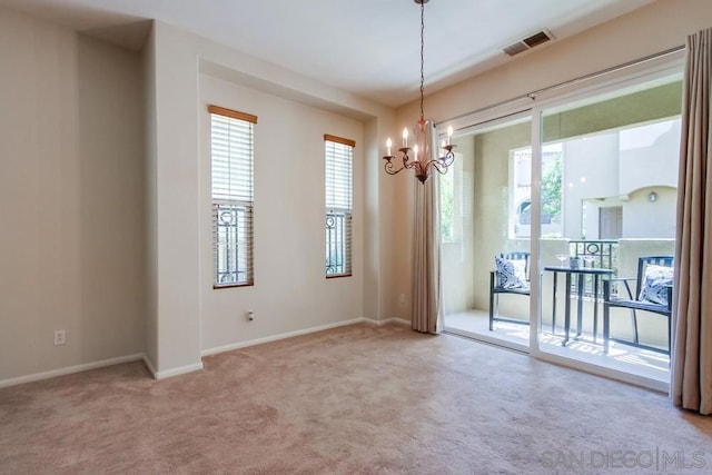 carpeted spare room with a notable chandelier