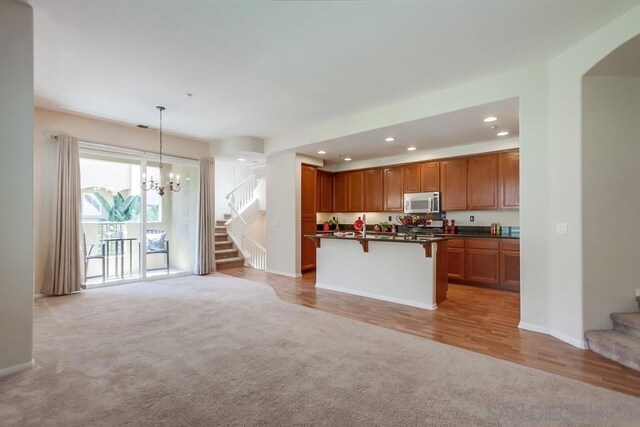 kitchen featuring pendant lighting, a kitchen breakfast bar, light hardwood / wood-style floors, and a kitchen island with sink