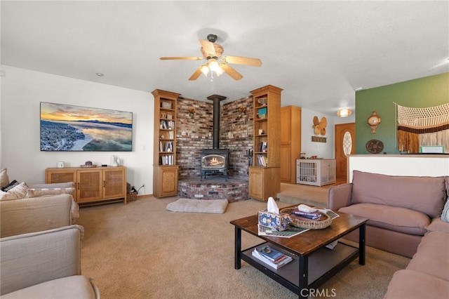 living room featuring ceiling fan, a wood stove, and light carpet