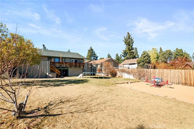 view of yard with a trampoline and a deck