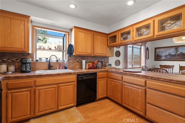 kitchen with backsplash, sink, light wood-type flooring, and black dishwasher