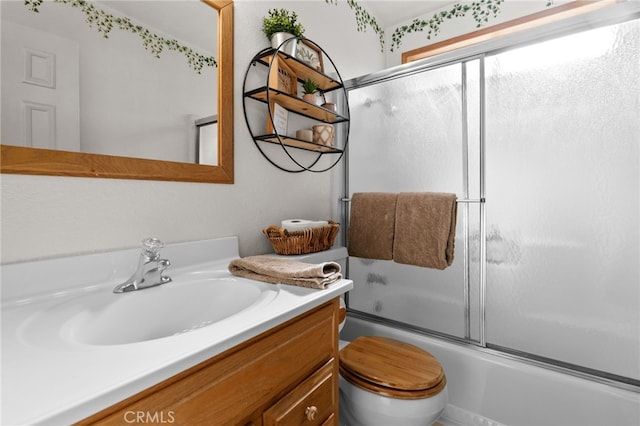 full bathroom with combined bath / shower with glass door, vanity, and toilet