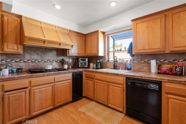 kitchen featuring backsplash, black appliances, sink, light hardwood / wood-style floors, and custom range hood