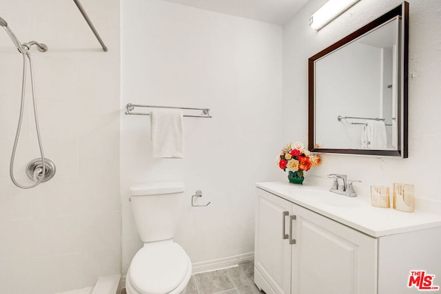 bathroom featuring vanity, tiled shower, tile patterned floors, and toilet