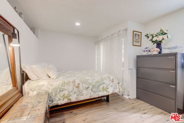 bedroom with a textured ceiling and light hardwood / wood-style flooring