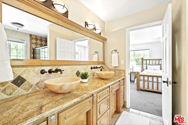 bathroom with backsplash, vanity, a healthy amount of sunlight, and a shower with shower door