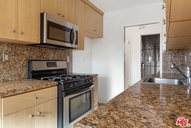 kitchen with stone counters, backsplash, stainless steel appliances, and sink