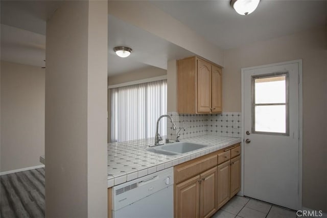 kitchen featuring tile counters, sink, light brown cabinets, backsplash, and white dishwasher