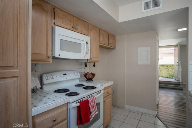 kitchen with tile countertops, light brown cabinets, light tile patterned floors, and white appliances