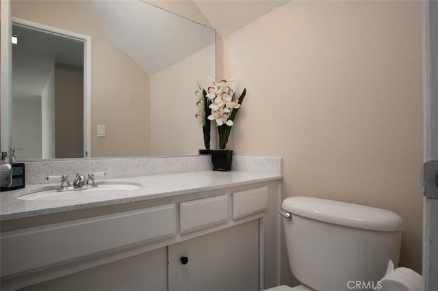 bathroom with vanity, toilet, and lofted ceiling