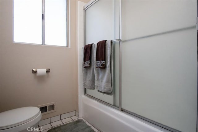 bathroom with tile patterned floors, toilet, and shower / bath combination with glass door