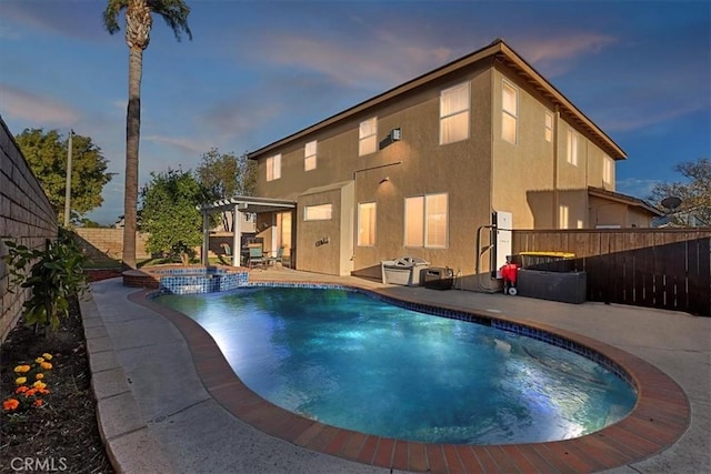 pool at dusk with an in ground hot tub, a patio, and a pergola