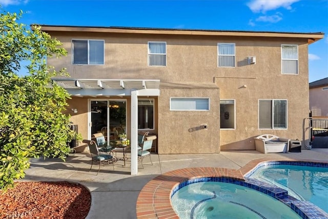 back of property featuring a swimming pool with hot tub, a patio area, and a pergola