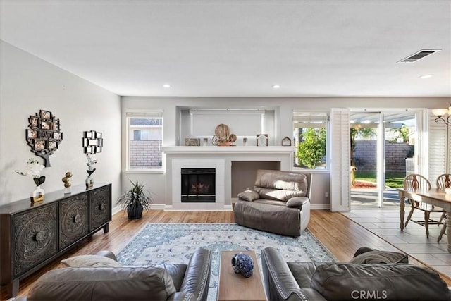 living room with plenty of natural light, a tile fireplace, and light hardwood / wood-style flooring