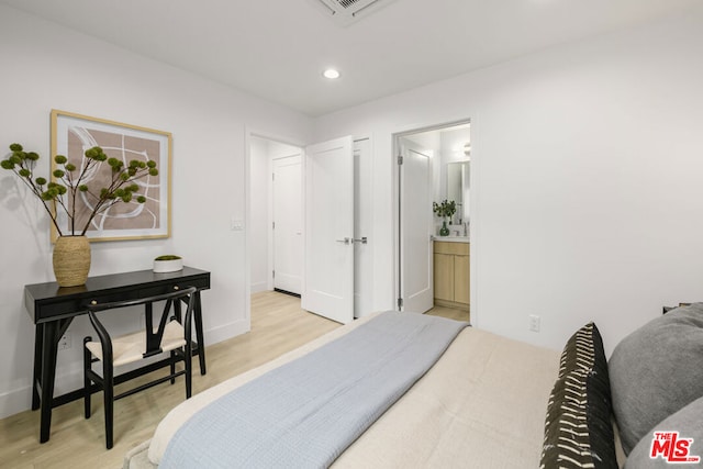 bedroom with light wood-type flooring and connected bathroom