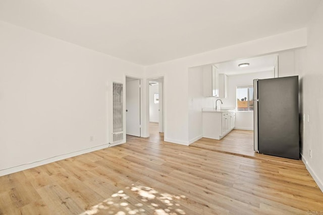 unfurnished living room with sink and light hardwood / wood-style flooring