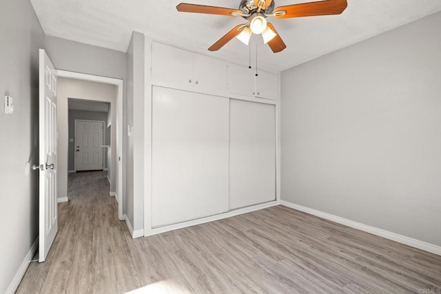 unfurnished bedroom featuring ceiling fan, a closet, and light wood-type flooring