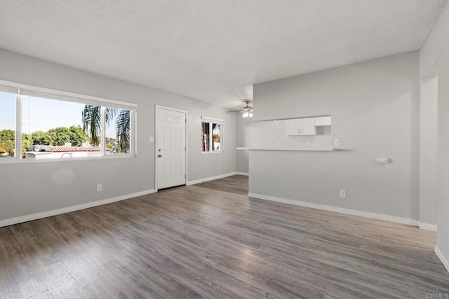 unfurnished living room with a textured ceiling, dark hardwood / wood-style floors, and ceiling fan